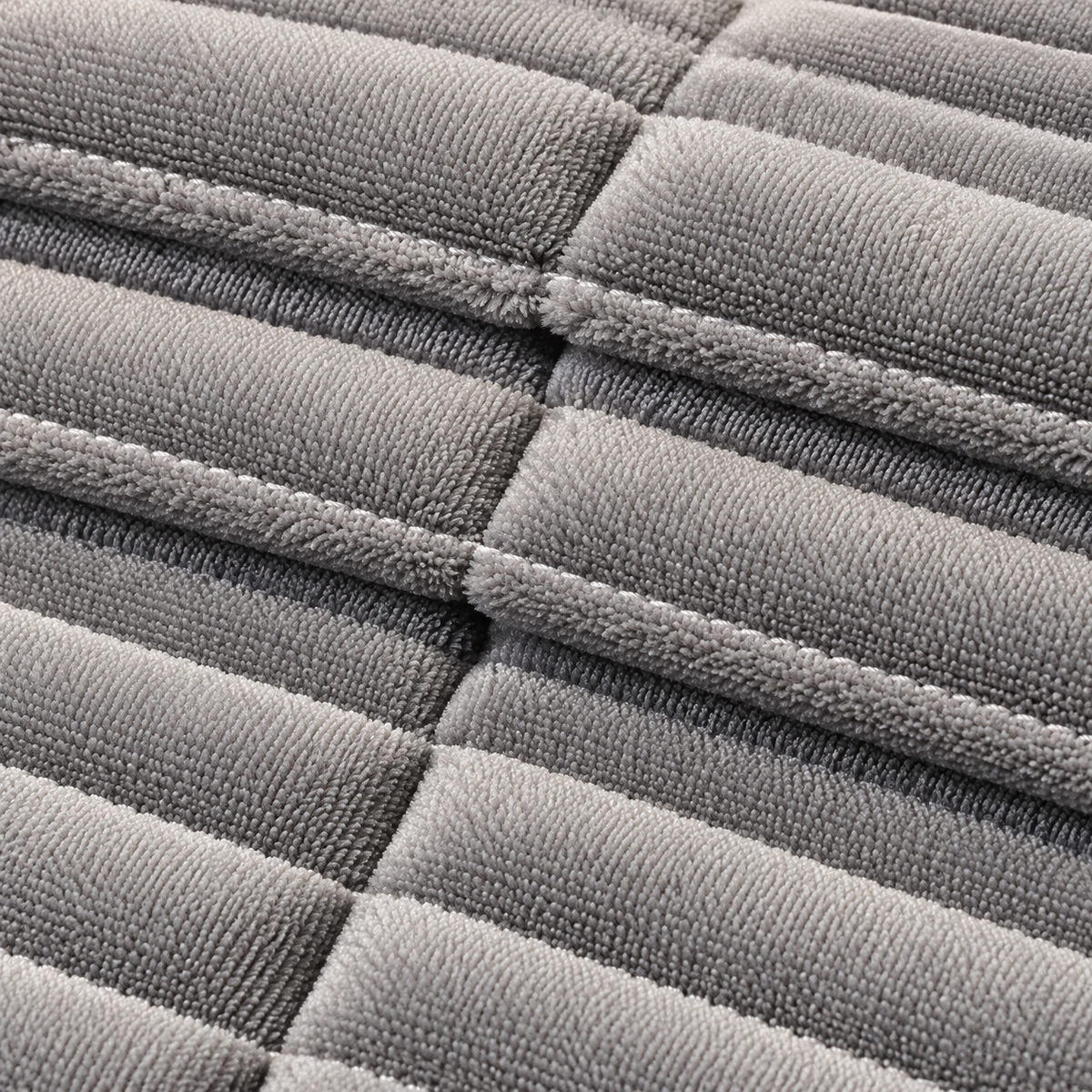 Close-up of a gray quilted fabric with stitched rectangular sections and a soft, plush texture.