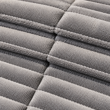Close-up of a gray quilted fabric with stitched rectangular sections and a soft, plush texture.