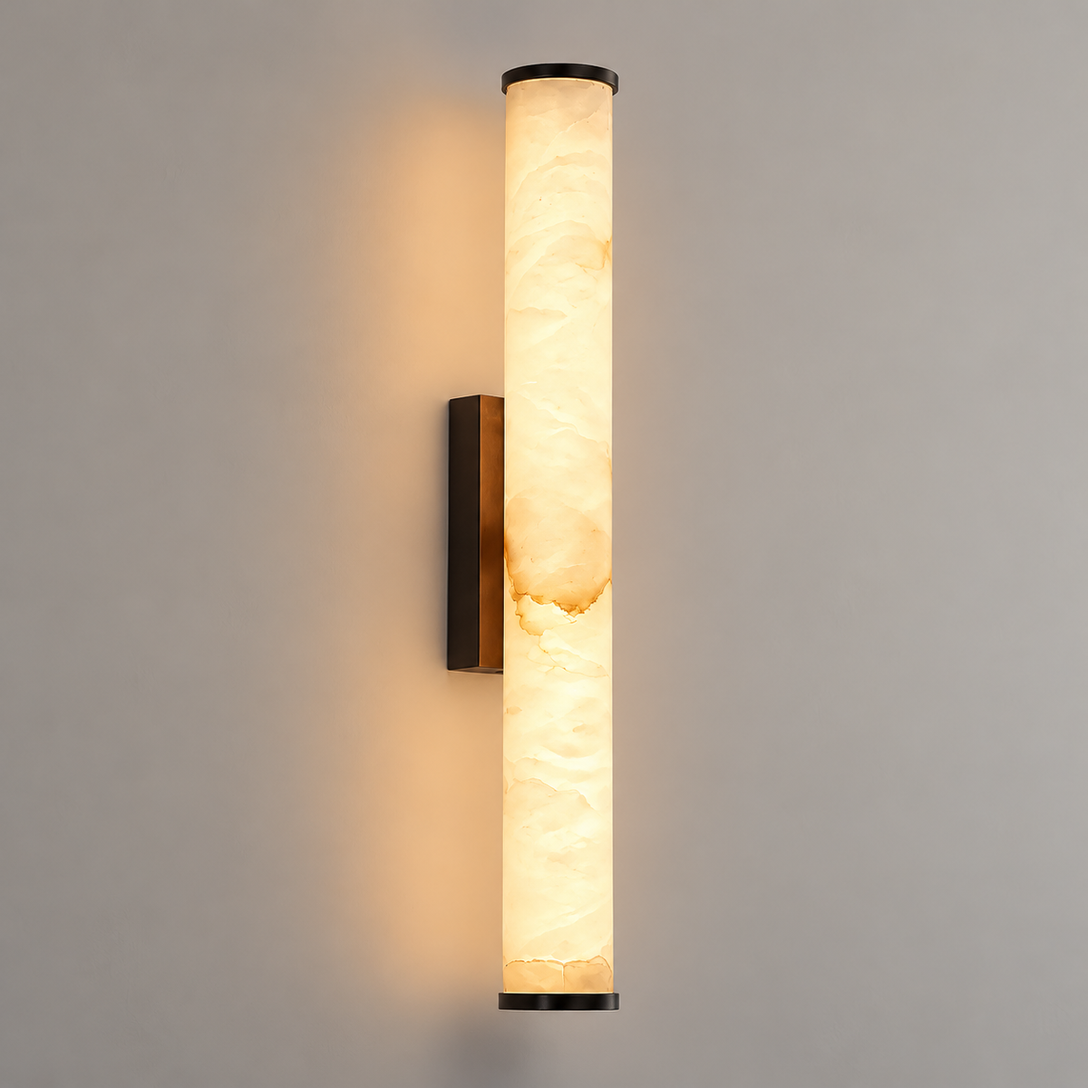 A modern wall-mounted vertical sconce with a cylindrical warm-white illuminated stone or acrylic shade and dark metal end caps and mounting bracket, shown against a plain light gray wall.