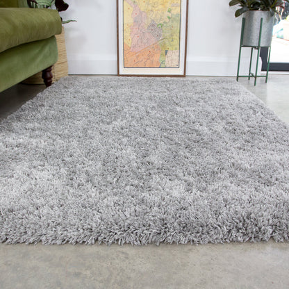 Gray shaggy rug in a room with a green chair and a map on the wall.