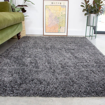 Gray shaggy rug in a living room with a green couch and framed map on the wall.