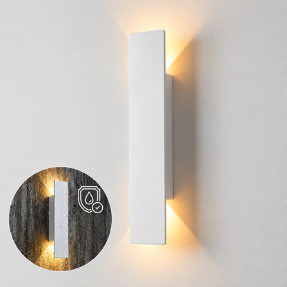 A modern vertical rectangular wall sconce in matte white, shown lit with warm yellow light on a white wall. A circular inset shows the fixture mounted on a dark textured wall with a water-resistant icon overlay.