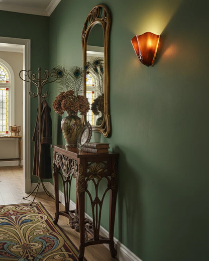 Vintage-style interior with a tall mirror, decorative stand, and wall sconce.