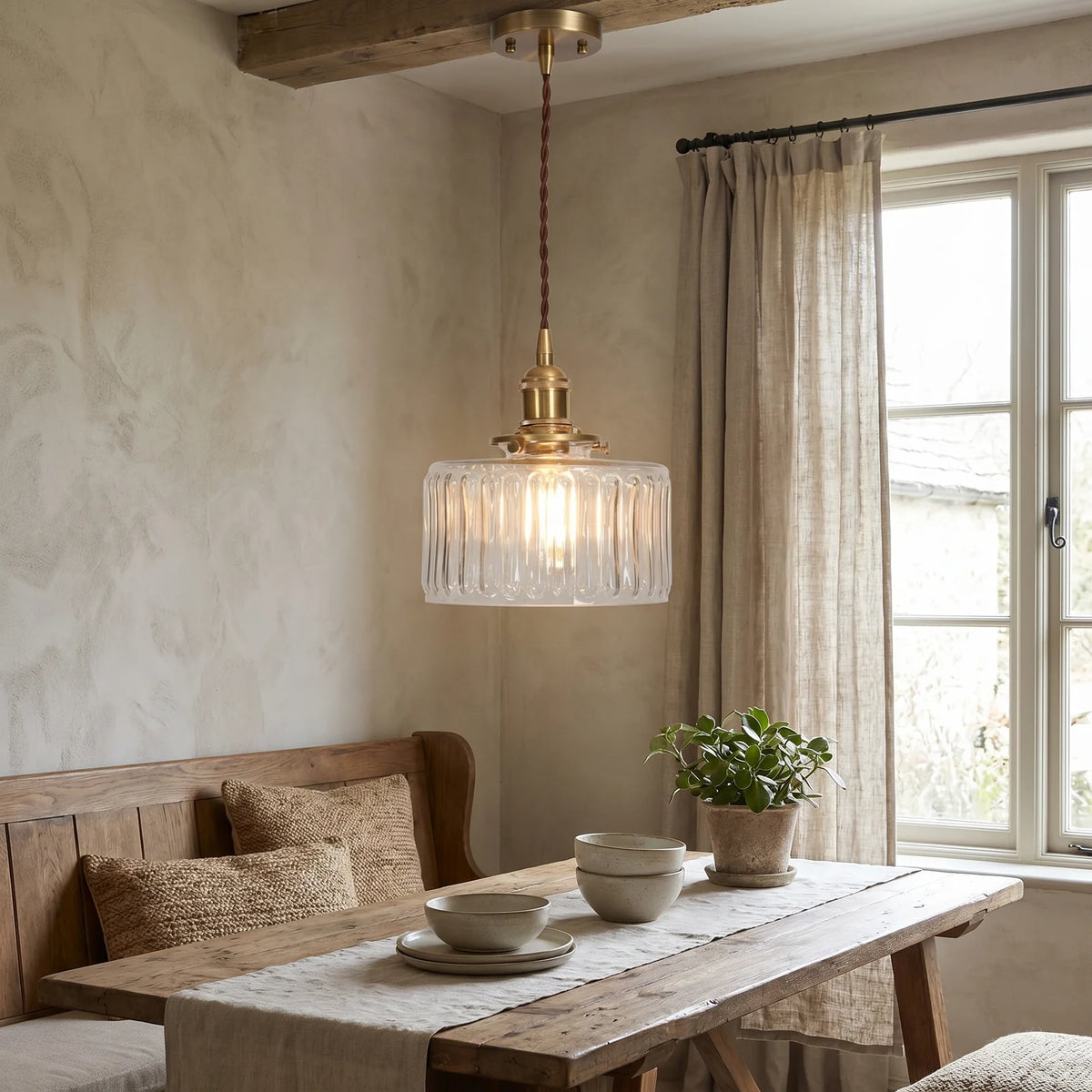 Dining room with wooden table, bench, and pendant light fixture.